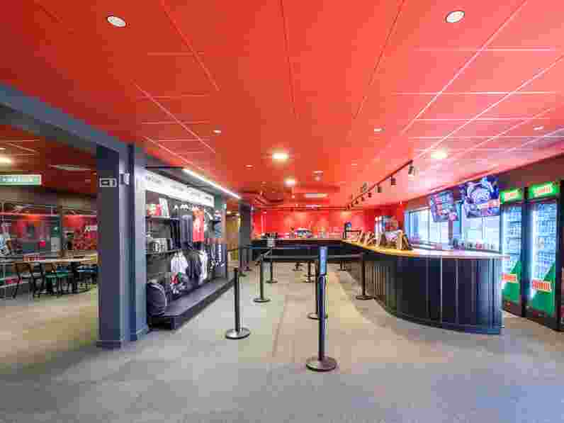 Red suspended acoustic ceiling with matching grids in trampoline park reception and shop area