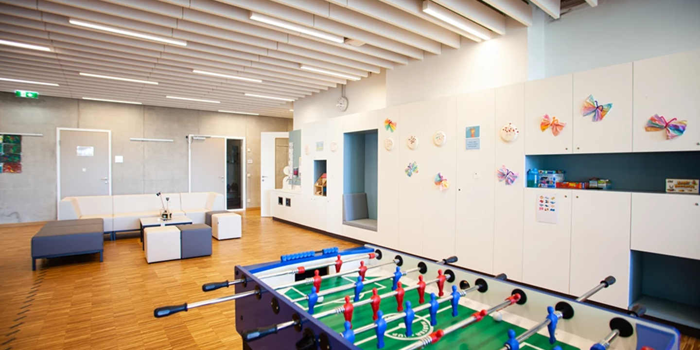 Salle avec babyfoot et canapés et baffles acoustiques au plafond