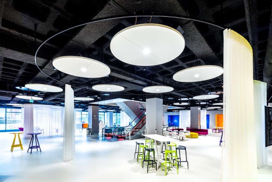 salle moderne avec grands îlots acoustiques ronds lumineux au plafond
