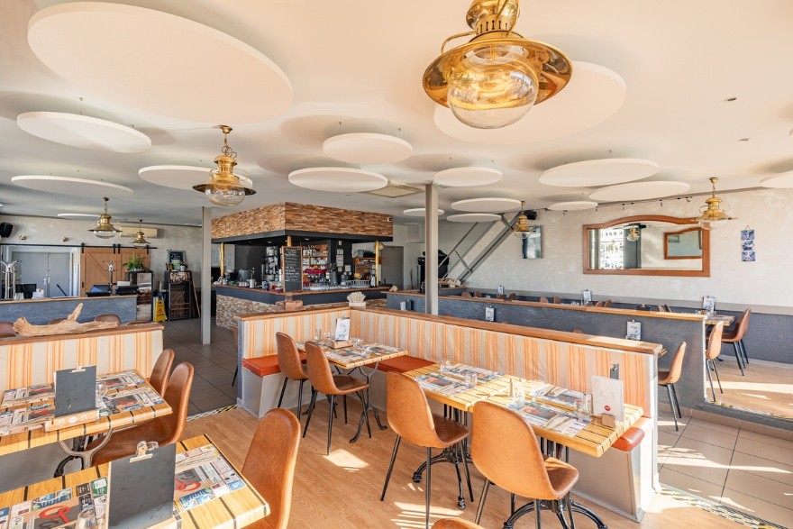 salle de restaurant avec chaises et tables et îlots acoustiques ronds au plafond