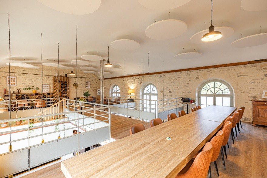 salle de restaurant avec grandes tables et îlots acoustiques ronds au plafond 