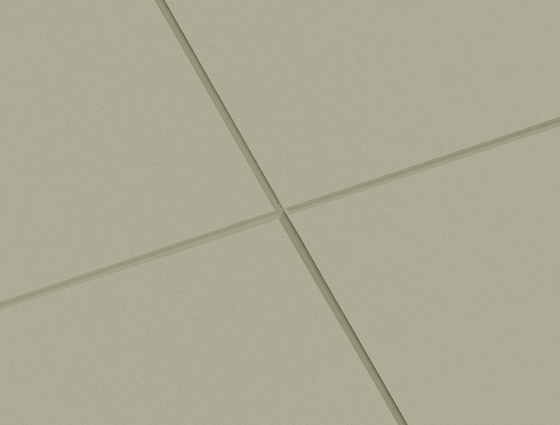 Close-up of light green acoustic ceiling tiles showing the fine surface texture and crisp recessed joints where the panels meet.