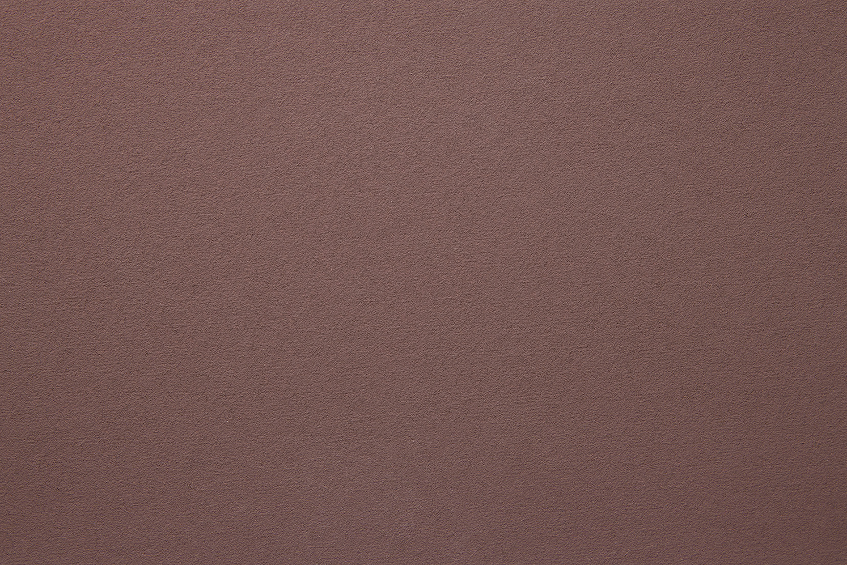 A close-up of a textured surface in a reddish-brown colour, resembling fine sandpaper or suede fabric. The texture appears even and consistent across the entire image.