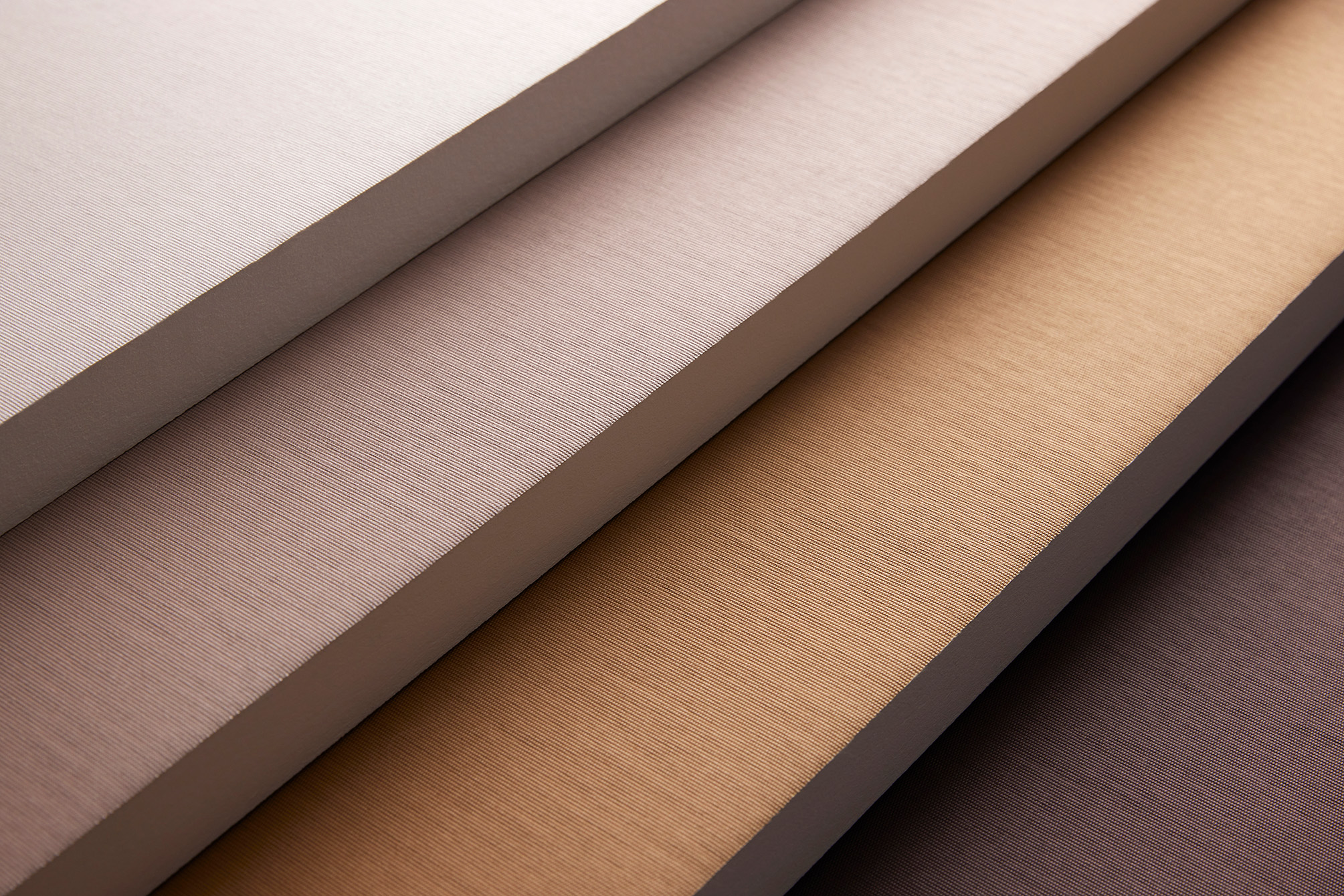 Close-up of layered acoustic panels in soft neutral colours, showing their textured fabric surfaces
