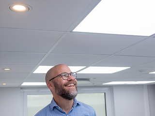 A smiling man looking up at an acoustic ceiling with integrated lighting panels