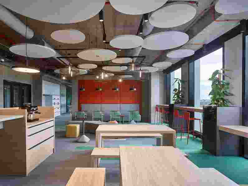 Free-hanging acoustic panels in colourful office lounge area