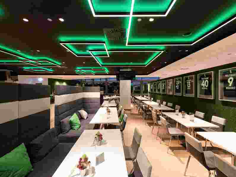 Black suspended acoustic ceiling with integrated lighting  in sports arena restaurant