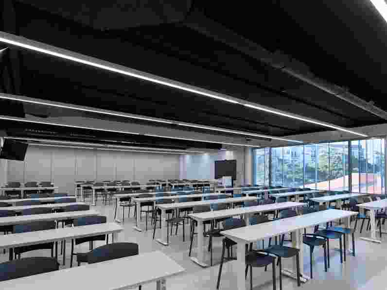 Černý akustický strop připevněný přímo k podhledu v univerzitní posluchárně