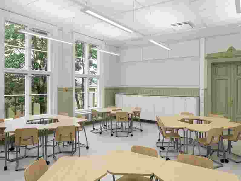 White, acoustic wall panels in classroom with groups of tables and chairs.