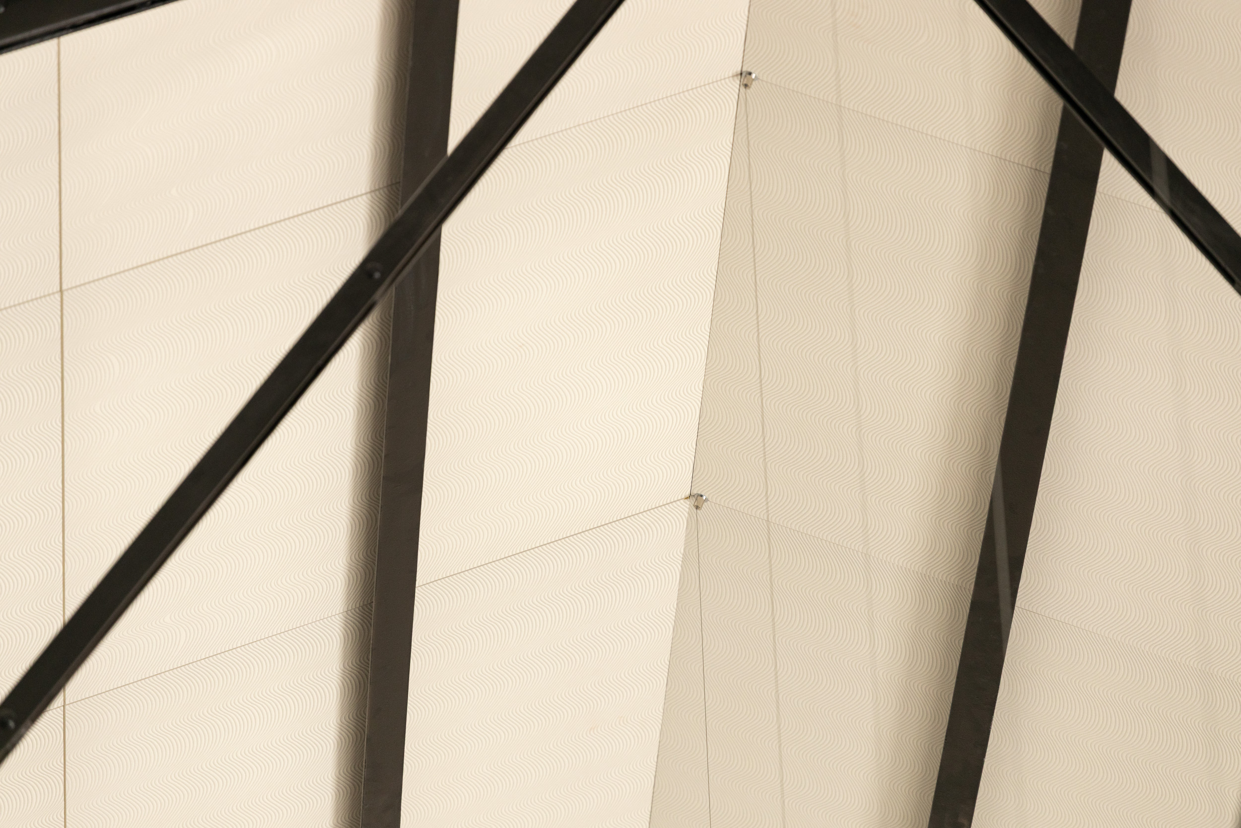 Lähikuvaa alakattoon liimatuista akustiikkalevyistä ja mustasta metallirakenteesta