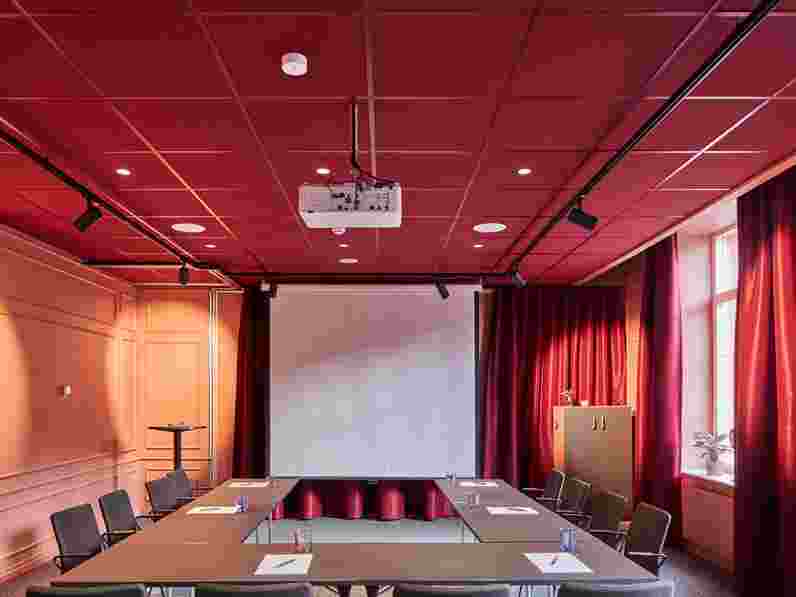 Conference room with dark red suspended acoustic ceiling with matching grids