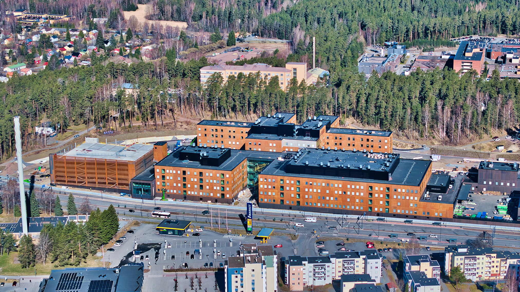 Ilmakuva suuresta modernista sairaalarakennuskokonaisuudesta, jota ympäröivät puut, pysäköintialueet ja tiet. Taustalla näkyy asuin- ja liikealueita.