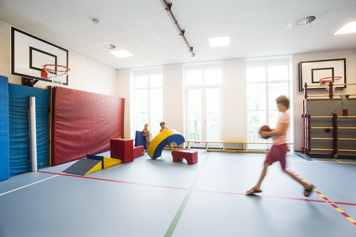 Children playing in small sports hall with acoustic ceiling system