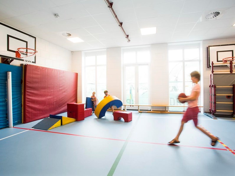 Children playing in small sports hall with acoustic ceiling system