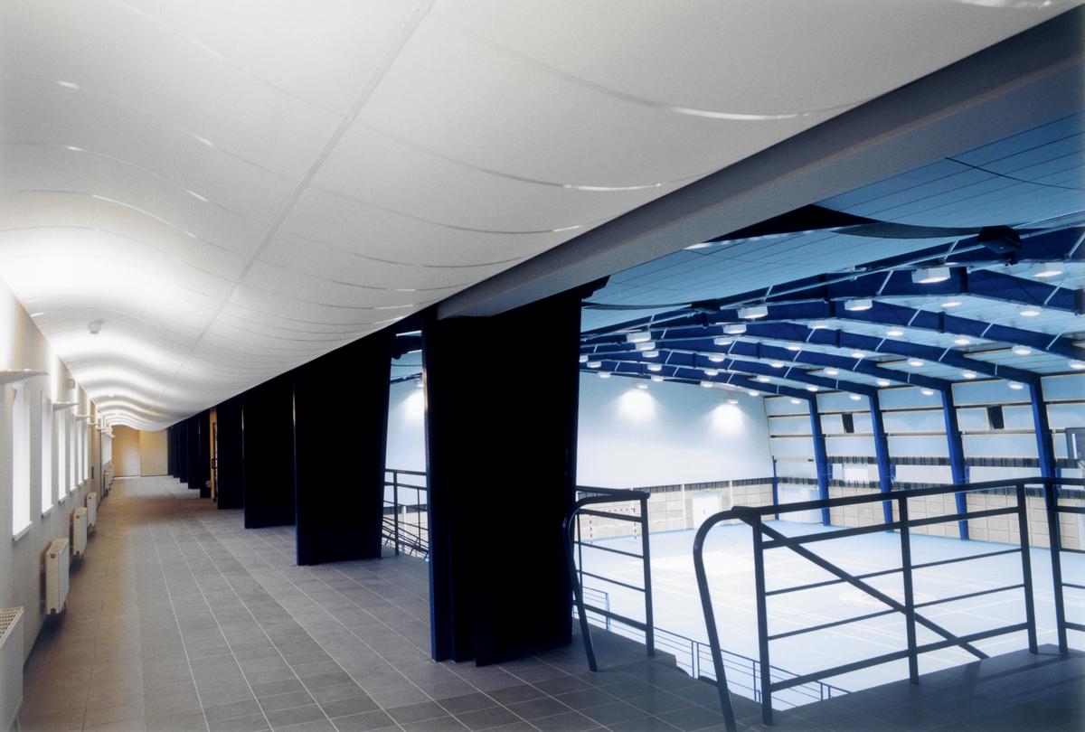 Curved acoustic ceiling tiles, Ecophon Focus&trade; Flexiform A, installed in sportshall corridor
