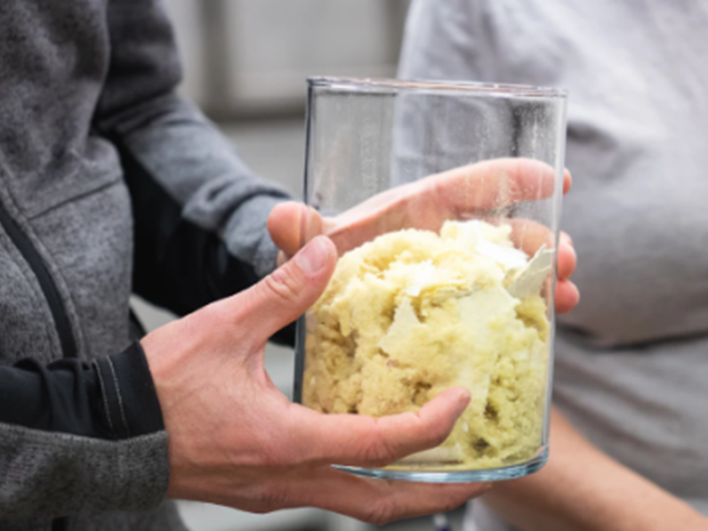 A person holding a glass jar filled with recycled glasswool